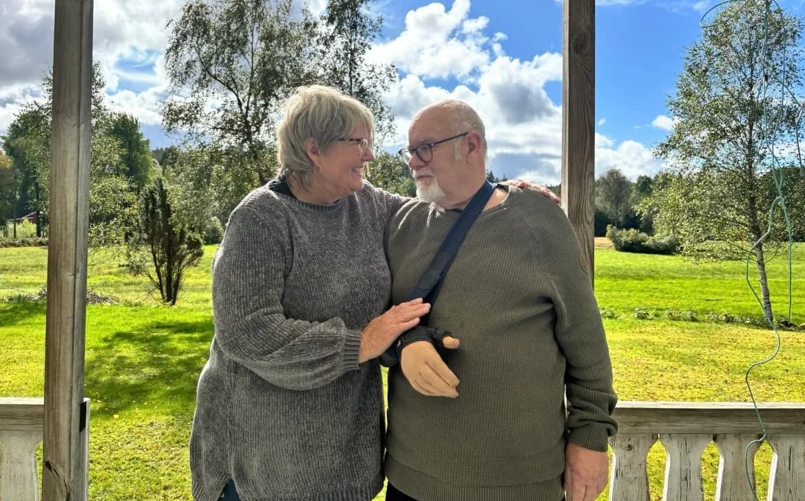 Ingela Stridh och Kjell Hansson står tillsammans på en veranda med en äng i bakgrunden.