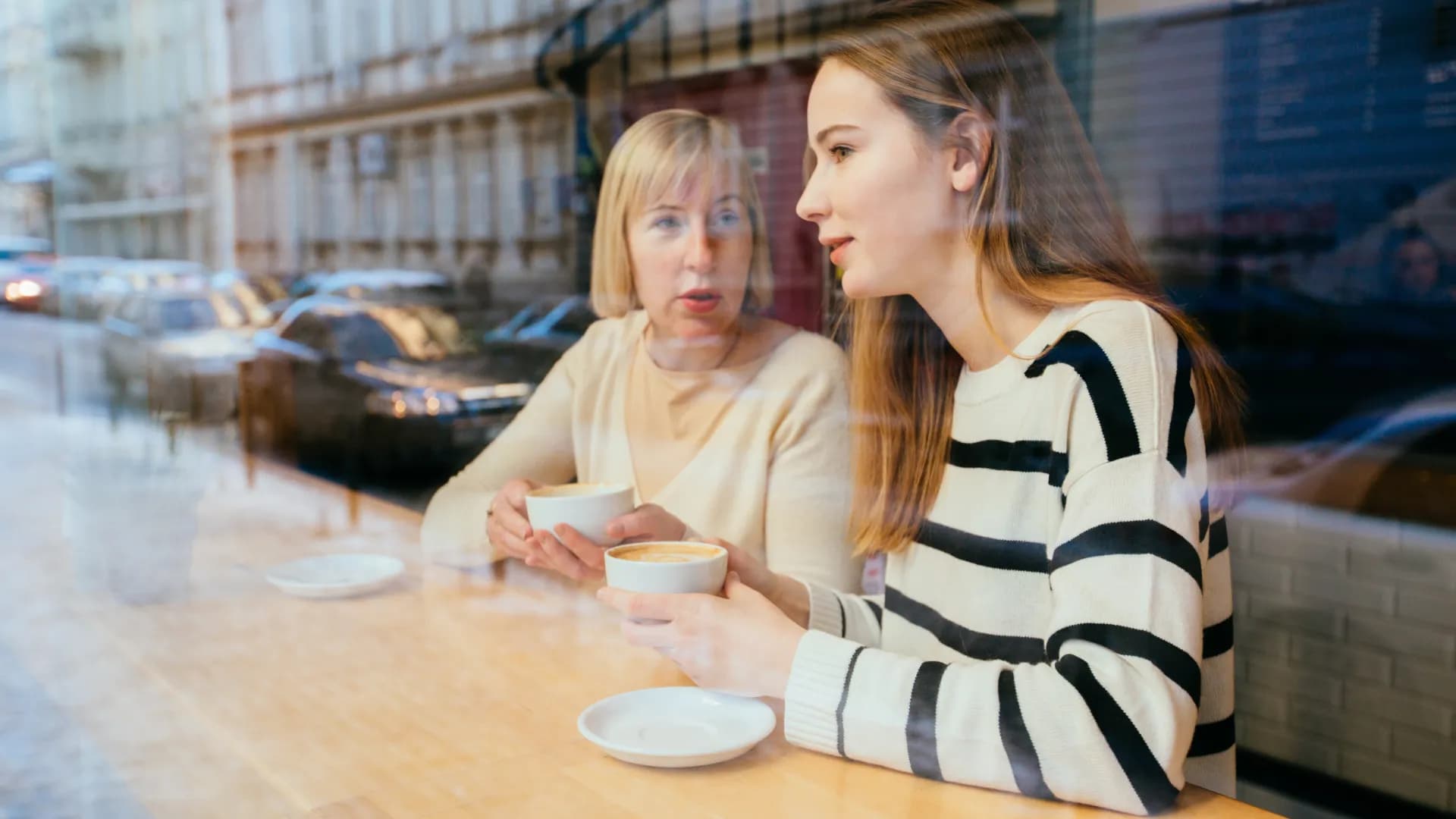 Mamma och dotter fikar på café.